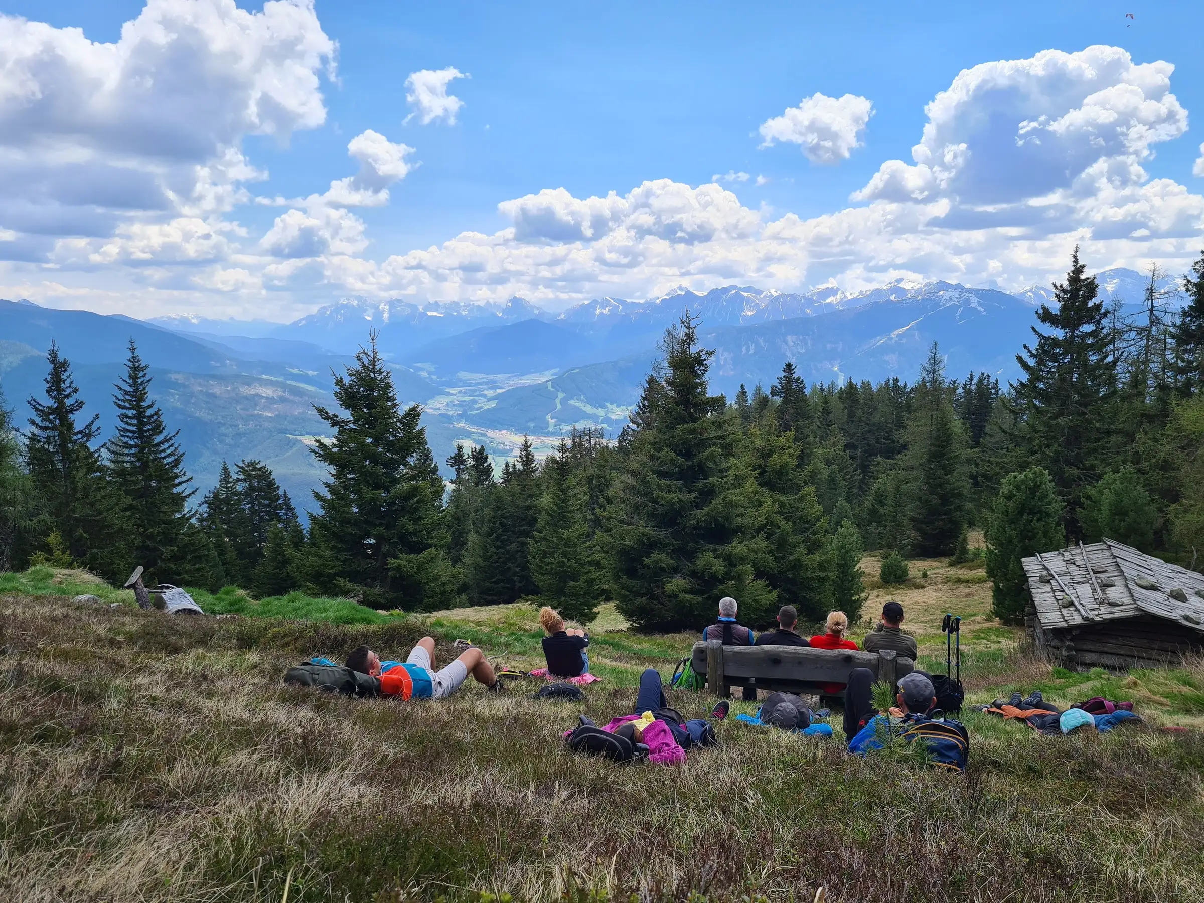 Wanderer rasten auf einer Almwiese mit Blick auf die Berge